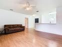 Spacious living room featuring wood flooring, a ceiling fan, and a comfortable couch for relaxation at 305 Erie Ct, Kissimmee, FL 34759