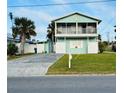 Two-story teal home with a balcony, driveway, and grassy yard at 3949 S Peninsula Dr, Port Orange, FL 32127