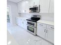 Modern kitchen featuring white cabinetry, stainless steel appliances, subway tile backsplash, and marble-like flooring at 3505 Pine Ridge Ct, Orlando, FL 32808