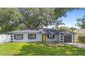 Inviting one-story home featuring a well-manicured lawn and a distinctive yellow front door at 3703 Pembrook Dr, Orlando, FL 32810