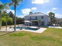 Backyard view of a private pool surrounded by lush greenery, a lounge area, and a well-manicured lawn at 10542 Wittenberg Way, Orlando, FL 32832