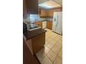 Traditional kitchen with tile flooring, wood cabinetry, white appliances, and a speckled countertop at 4663 Montauk St, Orlando, FL 32808