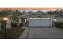 House exterior at dusk with a white garage door and landscaping at 2584 Dividing Creek Path, The Villages, FL 32162