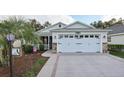 One-story house with white siding, stone accents, and a two-car garage at 2584 Dividing Creek Path, The Villages, FL 32162