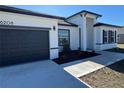 Single-Gathering home featuring a black garage door, modern landscaping, and a welcoming entrance at 6208 Sw 129Th St, Ocala, FL 34473