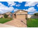 Tan house with red shutters, paver driveway, and landscaped lawn at 10063 Malmsbury Rd, Orlando, FL 32829