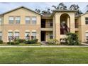 Two-story apartment building with neutral stucco, arched entryway, landscaped lawn, and visible windows at 2878 Club Cortile Cir # A, Kissimmee, FL 34746