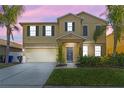 Two-story home featuring manicured landscaping, a welcoming entrance, and a two car garage, at dusk at 1911 Betsy Ross Ln, St Cloud, FL 34769