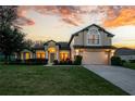 Inviting two-story home featuring manicured lawn, elegant arched windows, a two-car garage, and warm exterior lighting at 36711 Alaqua Ct, Eustis, FL 32736