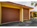 Attached garage with brown overhead door and yellow exterior walls at 4916 Fiji Cir # 11, Orlando, FL 32808