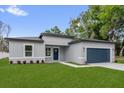 Landscaped home featuring a blue garage door, manicured lawn, and contemporary style at 494 Marion Oaks Trl, Ocala, FL 34473