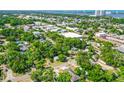 Wide aerial shot showing lush greenery of a residential neighborhood, local businesses and the city and ocean beyond at 535 Madison Ave, Daytona Beach, FL 32114
