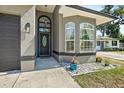 Close up of front entry featuring an arched doorway, decorated glass, exterior lighting, and lush landscaping at 535 Madison Ave, Daytona Beach, FL 32114