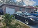 Exterior view of the home featuring a garage, lawn, and parked vehicle in the driveway at 16 N Lancelot Ave, Orlando, FL 32835
