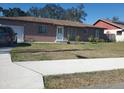 Tan single-story house with a front yard, driveway, and attached garage at 16 N Lancelot Ave, Orlando, FL 32835