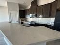 This kitchen showcases an island with quartz counters, stainless appliances, and dark wood cabinets at 5286 Teirgarten St, Saint Cloud, FL 34771