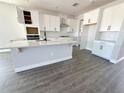 New kitchen features white cabinets, an island with seating, and stainless steel appliances at 5280 Teirgarten St, Saint Cloud, FL 34771