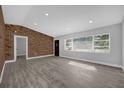 Spacious living room with brick accent wall, gray vinyl floors, recessed lighting, and large windows at 5023 Golf Club Pkwy, Orlando, FL 32808