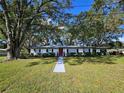 White brick ranch home with red door, landscaping, and walkway at 5528 Flamingo Ave, Lakeland, FL 33809