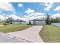 Well-manicured lawn and concrete driveway leading to a lovely one-story home with an attached two-car garage at 8908 Sw 133Rd Ln, Ocala, FL 34473