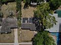 Birds-eye view of a home with solar panels on the roof, surrounded by mature trees and green lawns at 5018 Figwood Ln, Orlando, FL 32808