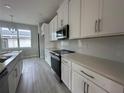 Open-concept kitchen with white cabinets, stainless steel appliances, quartz countertops, and tile backsplash at 1344 Lumpini St, Saint Cloud, FL 34771