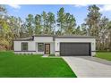 A modern home with white exterior, black trim, a dark gray garage door and a green lawn at 15123 Sw 61St Court Rd, Ocala, FL 34473