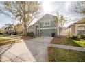 Well-manicured front lawn with mature tree, two car garage, and two story home at 2142 Brandywine Falls Way, Orlando, FL 32824