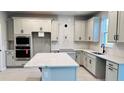 Bright kitchen featuring white cabinets, stainless steel appliances, and a large island with a quartz countertop at 1165 Basalt Ln, Sanford, FL 32771