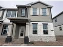 Two-story home showcasing a blend of stone and siding accents, complemented by contrasting black and white trim at 1364 Lumpini St, St Cloud, FL 34771