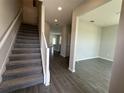 Bright foyer with staircase and views of open-concept living spaces featuring hard surface floors at 1364 Lumpini St, St Cloud, FL 34771