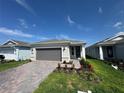 Charming single-story home with brick-paved driveway, gray garage door, and beautifully landscaped front yard at 2322 Lily Bloom Rd, St Cloud, FL 34771