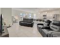 Spacious living room featuring tile floors, modern furniture, and an open-concept design into the kitchen area at 7889 Penrose Pl, Wildwood, FL 34785