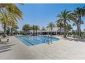 Beautiful pool with community center in the background, surrounded by palm trees and lounge chairs at 7889 Penrose Pl, Wildwood, FL 34785