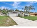 View of the exterior featuring a two-car garage, solar panels, and a lengthy driveway at 1053 E Hancock Dr, Deltona, FL 32725