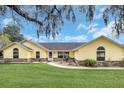 Inviting yellow home with stone accents, arched windows, and manicured lawn at 4750 Rummell Rd, St Cloud, FL 34771