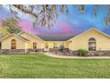 Inviting yellow home with stone accents, arched windows, and manicured lawn at 4750 Rummell Rd, St Cloud, FL 34771