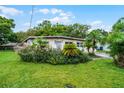 Inviting single-story house surrounded by lush greenery, including vibrant flowers, palm trees, and a well-maintained lawn at 4908 Seminole Ave, Winter Park, FL 32792