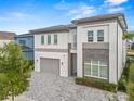 Two-story home featuring a gray paved driveway, a gray roof and stone accents at 1529 Corolla Ct, Reunion, FL 34747