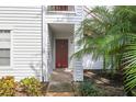 Condo entrance with a red door, white siding, and manicured landscaping at 11574 Westwood Blvd # 1112, Orlando, FL 32821