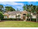 Charming one-story home showcasing a manicured front lawn, stone accents, and mature palm trees at 943 Elm Harbor Ct, Lake Mary, FL 32746