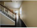 Inviting hallway with hardwood floors, a staircase with wooden railings, and neutral-colored walls at 13910 Dove Wing Ct, Orlando, FL 32828