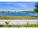 Scenic view of a tranquil pond surrounded by lush green grass and community buildings at 11218 Pixie Mandarin Ct, Winter Garden, FL 34787