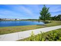 Scenic view of a tranquil pond surrounded by lush green grass and community buildings at 11218 Pixie Mandarin Ct, Winter Garden, FL 34787