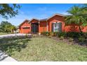 Well-maintained front yard with lush green grass, landscaping, and a charming one-story home in the background at 1221 Glendora N Rd, Kissimmee, FL 34759