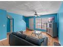 Bright living room with blue walls, a comfortable sofa, ceiling fan, and a large window for natural light at 3390 Cedar Spring Pl # 163, Winter Park, FL 32792