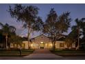 Inviting home featuring arched windows, a well-manicured lawn, mature trees, and a tile roof at 8681 Crested Eagle Pl, Sanford, FL 32771