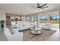 Living room featuring white furniture, modern ceiling fan, large windows to the outside, and an open view to the kitchen at 3303 Kayak Way, Orlando, FL 32820