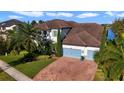 Elegant two-story home with a three-car garage, brick driveway and lush tropical landscaping at 16659 Broadwater Ave, Winter Garden, FL 34787