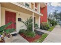 Inviting townhouse entrance showcasing a red door, colorful landscaping, and a cozy, covered porch at 4786 Tangerine Ave # 4786, Winter Park, FL 32792